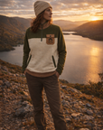 Woman wearing the Paws & Peaks Ascent Fleece in olive and cream, standing on a hillside at golden hour